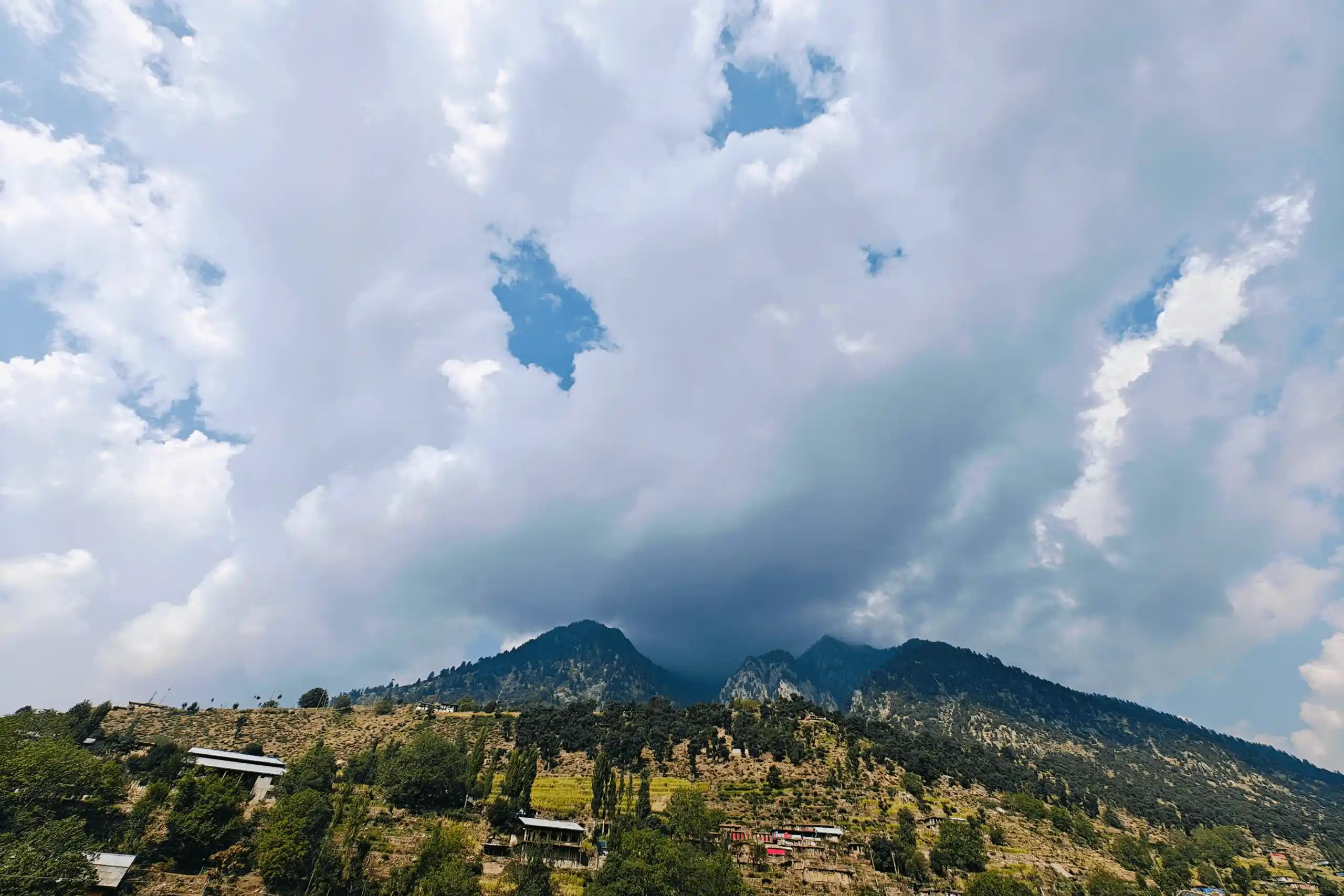 Mountain peaks under a cloudy sky, suggesting luxury escapes to scenic destinations.