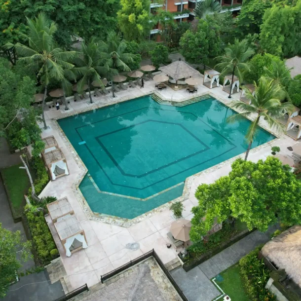 An aerial view of a large, inviting swimming pool surrounded by lush greenery and private cabanas, evoking the luxury found in resorts with private pools in Pakistan.