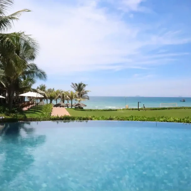 An infinity pool overlooking a tropical beach with palm trees and the ocean, representing a wide range of resort activities available.