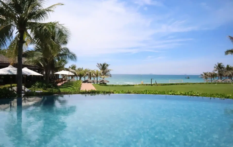 An infinity pool overlooking a tropical beach with palm trees and the ocean, representing a wide range of resort activities available.