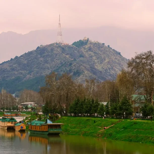 A tranquil view of houseboats on a river with a mountain in the background, a scene that represents some of the Top Resorts Near Islamabad.