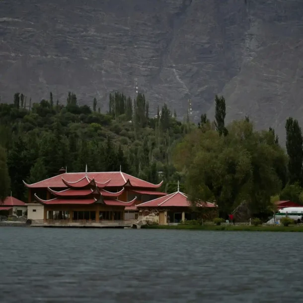 A cozy resort cottage with a balcony overlooking a serene lake and mountains, representative of Hidden Gem Resorts Pakistan.