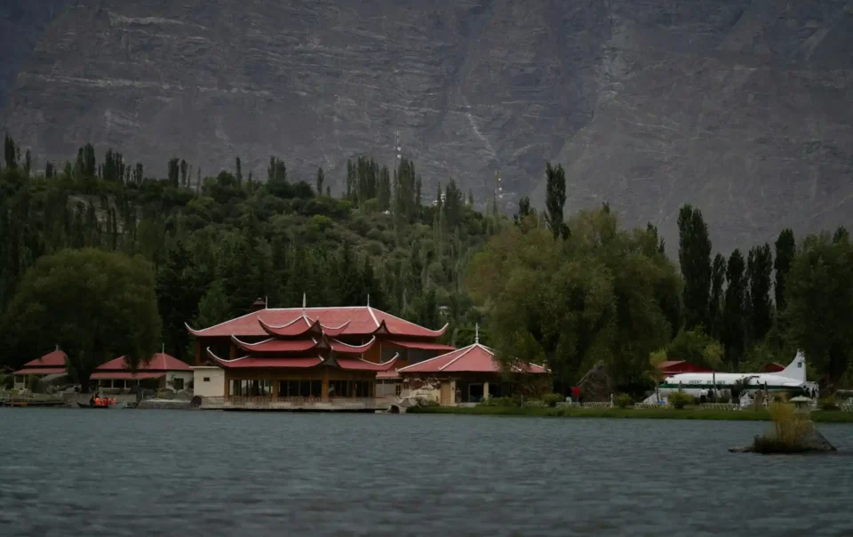 A cozy resort cottage with a balcony overlooking a serene lake and mountains, representative of Hidden Gem Resorts Pakistan.
