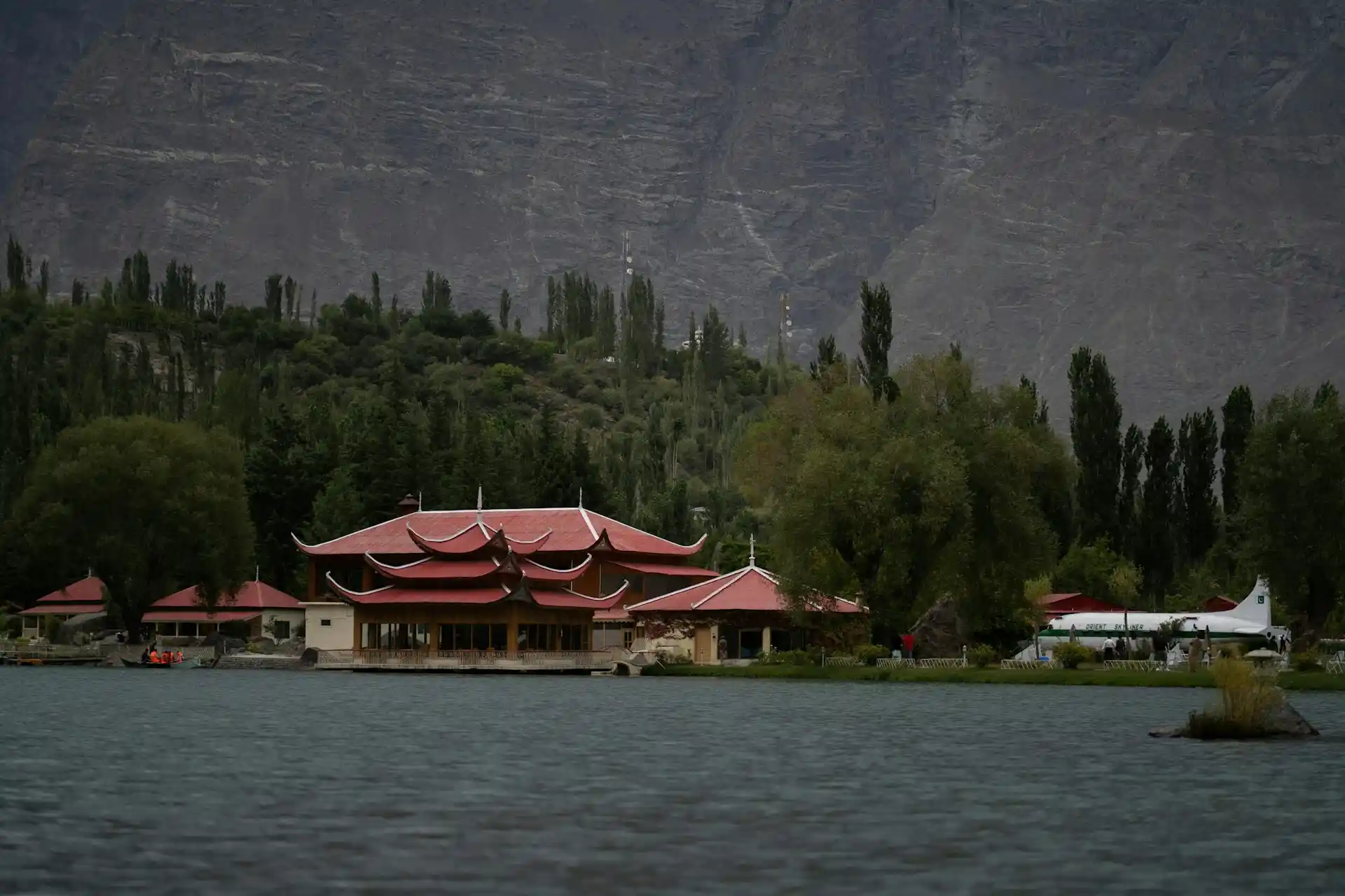 A cozy resort cottage with a balcony overlooking a serene lake and mountains, representative of Hidden Gem Resorts Pakistan.