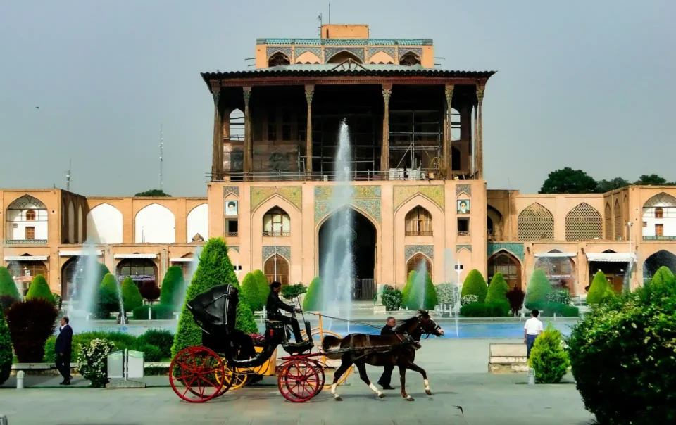 A grand palace with fountains and a horse-drawn carriage in a beautiful garden, symbolizing the luxury and scenic beauty of Staycations at Resorts.