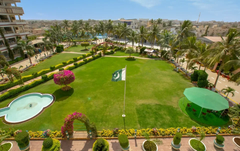 A lush green lawn with a Pakistani flag, surrounded by resort buildings, representing a spacious and professional venue at one of the Best Resorts for Team Building in Pakistan.