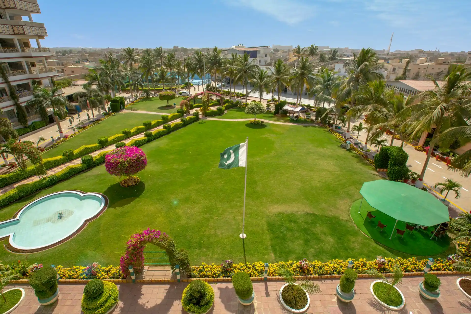 A lush green lawn with a Pakistani flag, surrounded by resort buildings, representing a spacious and professional venue at one of the Best Resorts for Team Building in Pakistan.